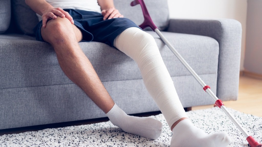 Young man with injured knee recovering at home_s Young man with injured knee recovering at home