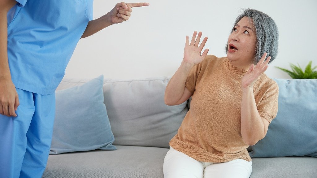 angry caregiver blaming or mistreating senior woman_s angry caregiver blaming or mistreating senior woman
