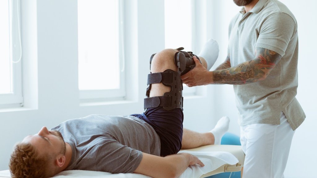 Young physiotherapist exercises in a bright medical office with his injured patient_s Young physiotherapist exercises in a bright medical office with his injured patient