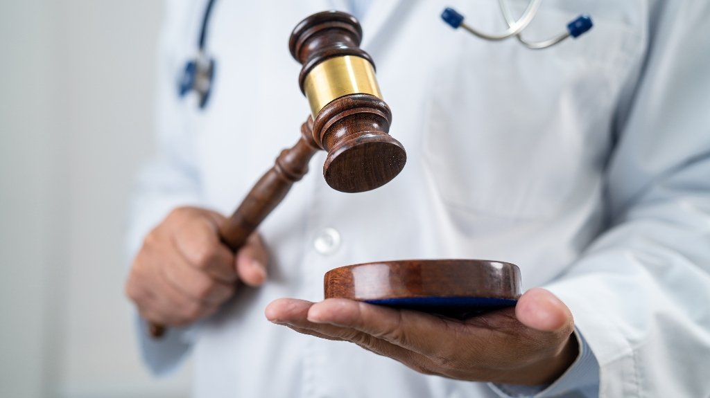 Doctor Holding Judge Gavel Representing Expert Medical Testimony Doctor Holding Judge Gavel Representing Expert Medical Testimony