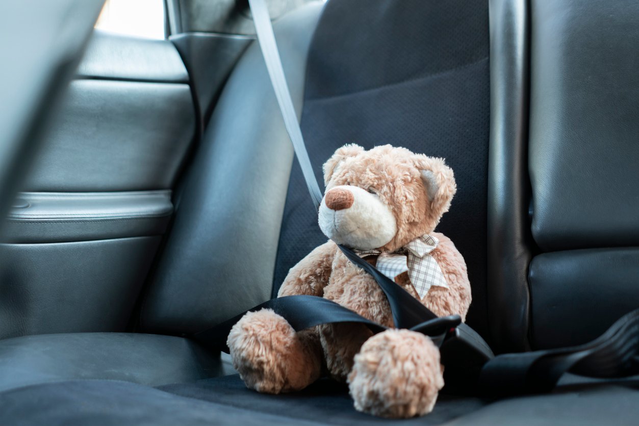 small teddy bear protected with safety belt in car, vehicle accident security Child’s teddy bear buckled with seatbelt showing child car safety after accident