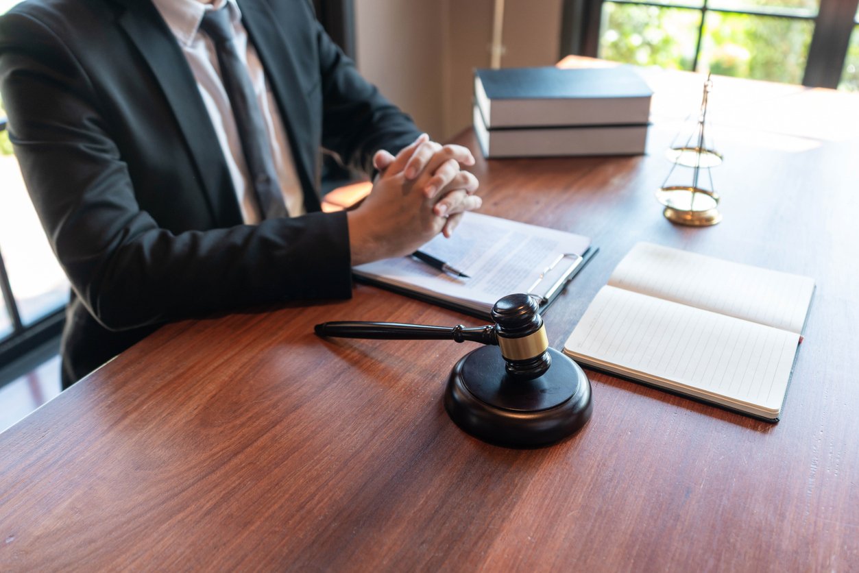 Justice concept an honorable judge sitting at the middle of the big wooden table with the judging hammer and the libra looking powerful. Lawyer at desk with gavel discussing punitive damages in personal injury case